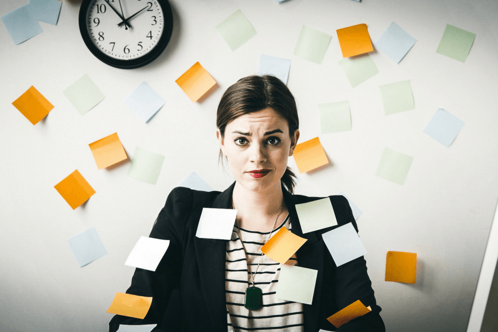 stressed looking woman sitting at desk with posted notes