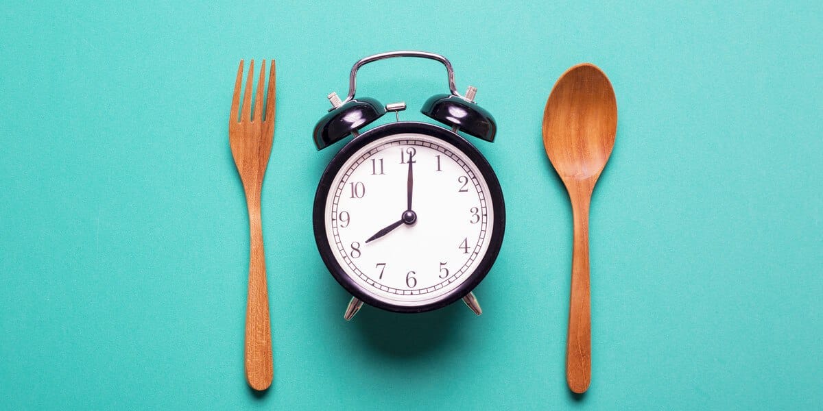 What Is Intermittent Fasting? Clock with fork and spoon representing eating times for intermittent fasting
